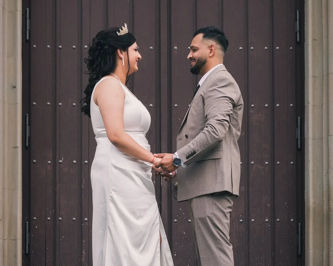 Alen and Gabriela hold hands in front of an impressive wooden door